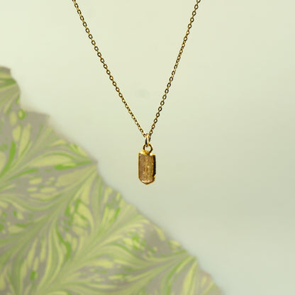 A gold chain necklace with a small rectangular Imperial Topaz pendant.