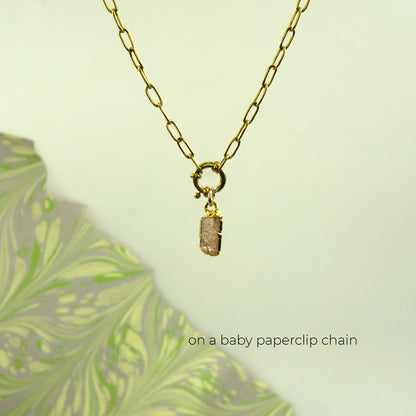A gold paperclip chain necklace with a small rectangular Imperial Topaz stone pendant.