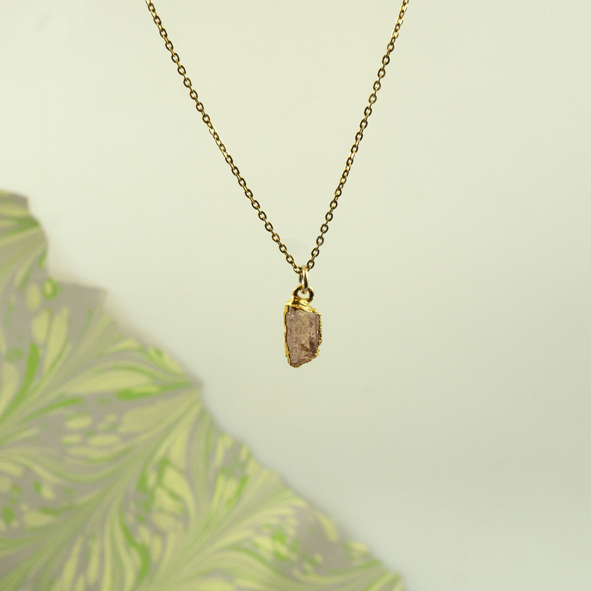 A gold chain necklace with a raw, irregular orange - peach Imperial Topaz crystal pendant.