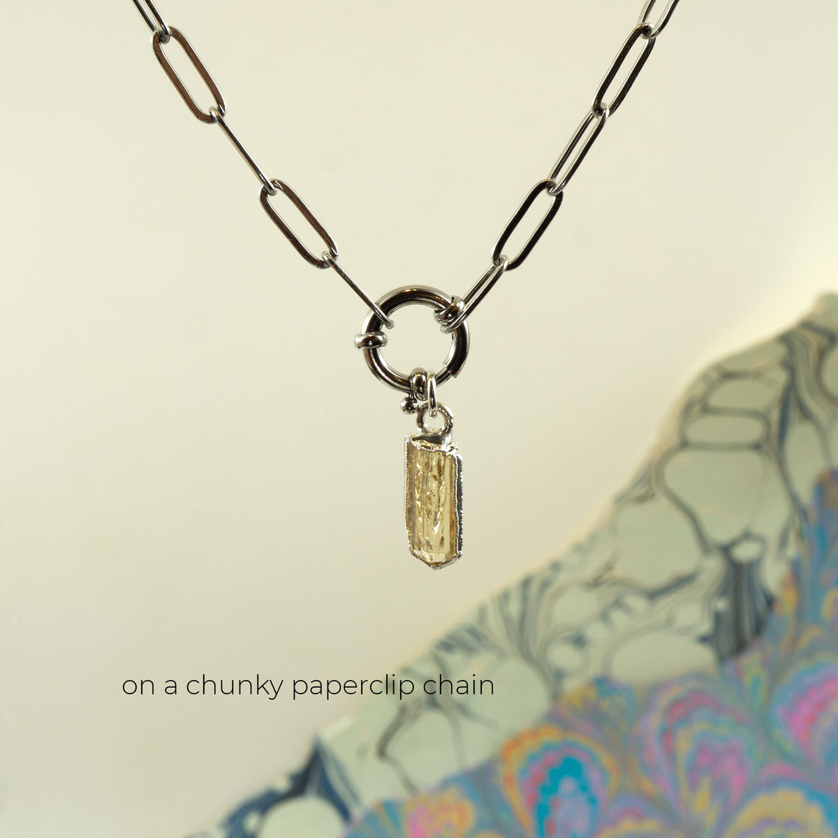 A silver paperclip chain necklace with a ring clasp and a small rectangular faceted Imperial Topaz crystal pendant.
