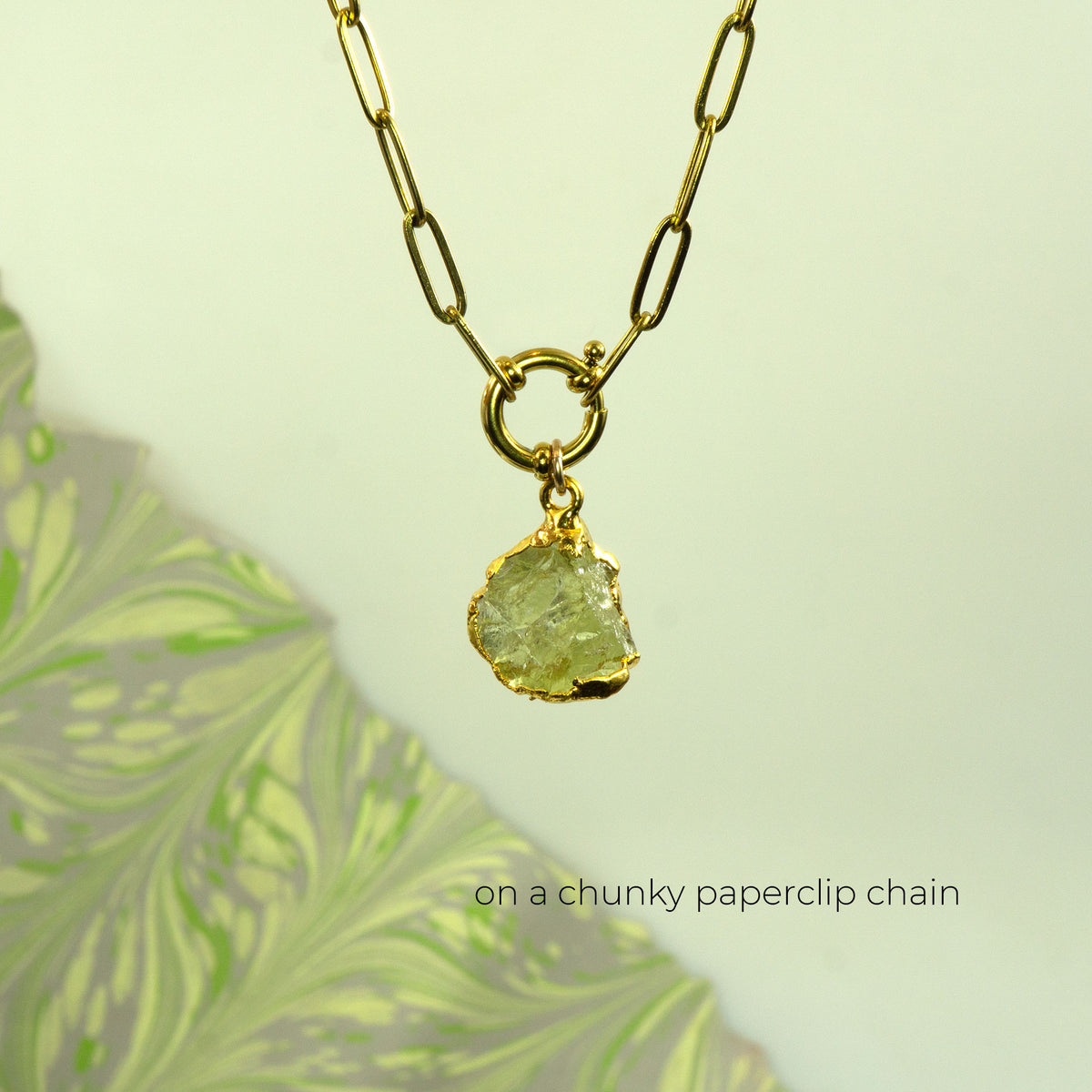 A gold paperclip chain necklace with a raw, irregular-cut light green Lemon Quartz gemstone pendant.