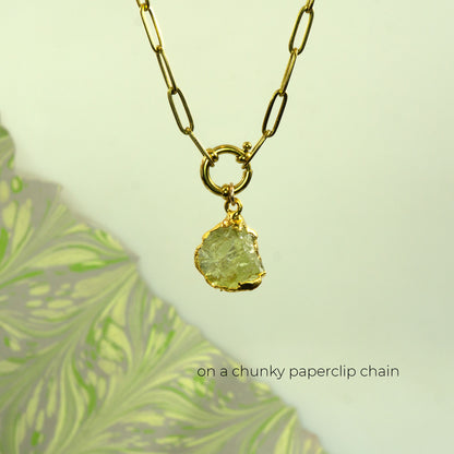 A gold paperclip chain necklace with a raw, irregular-cut light green Lemon Quartz gemstone pendant.