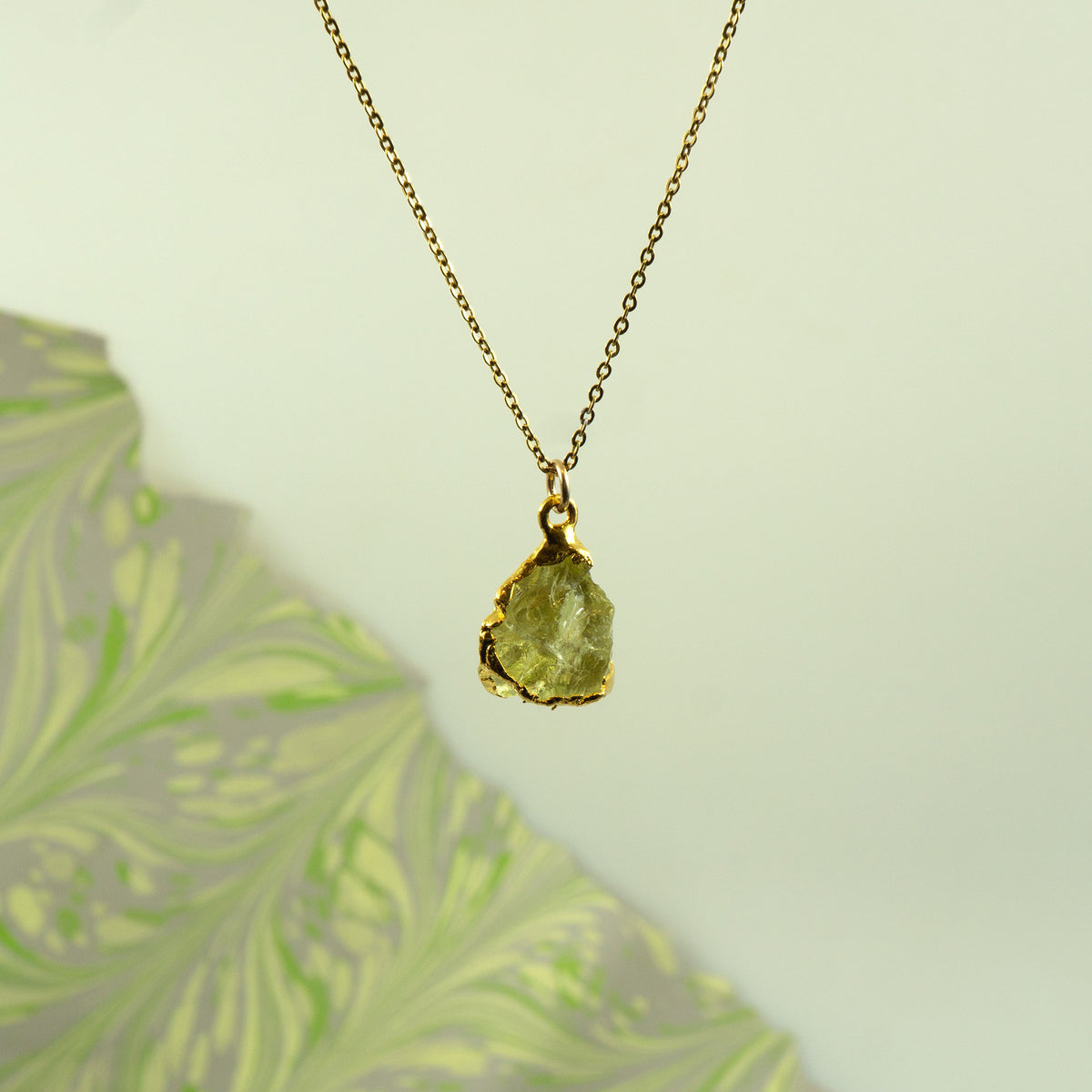 A gold chain necklace with a raw, irregular-cut Lemon Quartz gemstone pendant