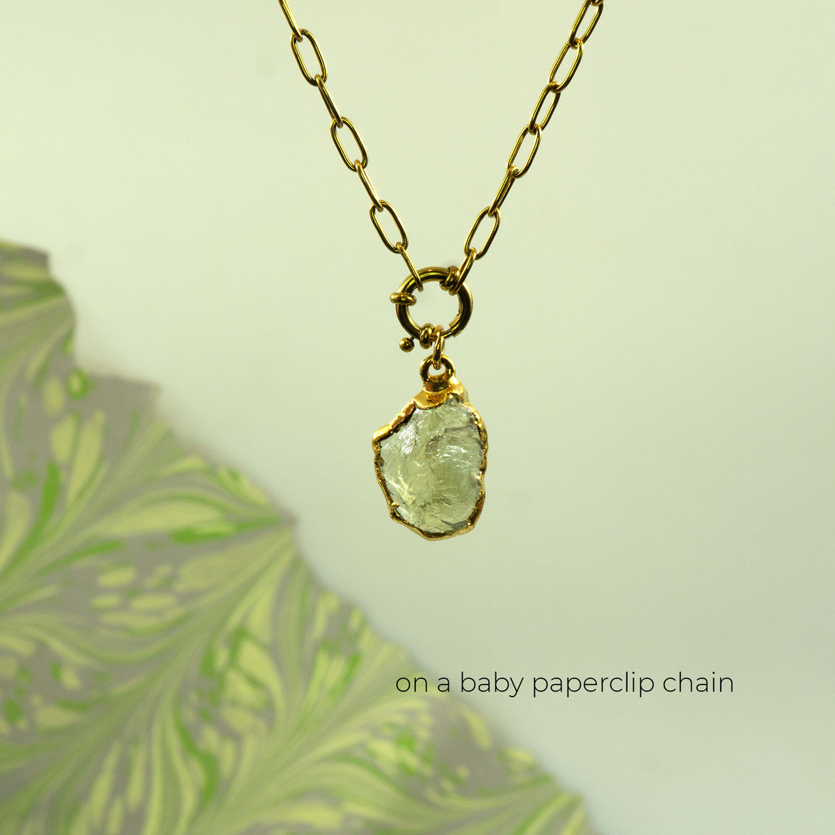 A gold paperclip chain necklace with a raw, irregular-cut clear Lemon Quartz gemstone pendant