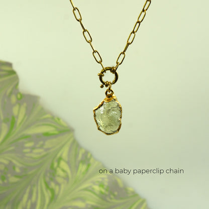 A gold paperclip chain necklace with a raw, irregular-cut clear Lemon Quartz gemstone pendant