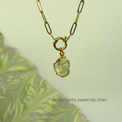 A gold necklace with a chunky paperclip chain and a raw, irregular-cut pale green Lemon Quartz gemstone pendant