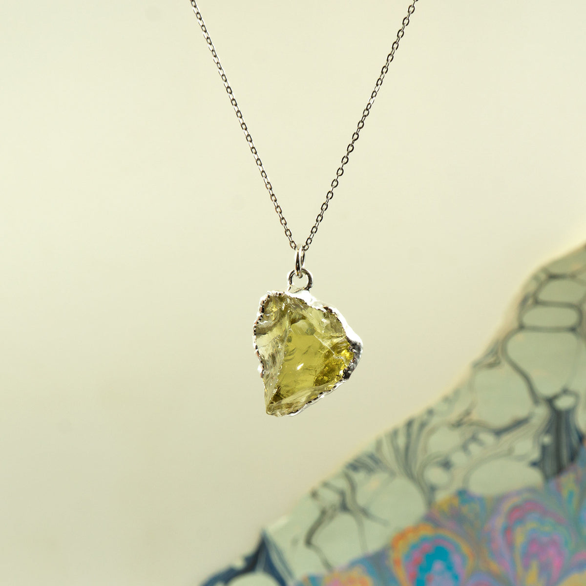 A raw yellow Lemon Quartz gemstone pendant necklace with a silver bezel, suspended on a delicate silver chain.