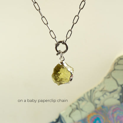A silver paperclip chain necklace with a small ring clasp holding a rough, irregular yellow-green Lemon Quartz gemstone pendant