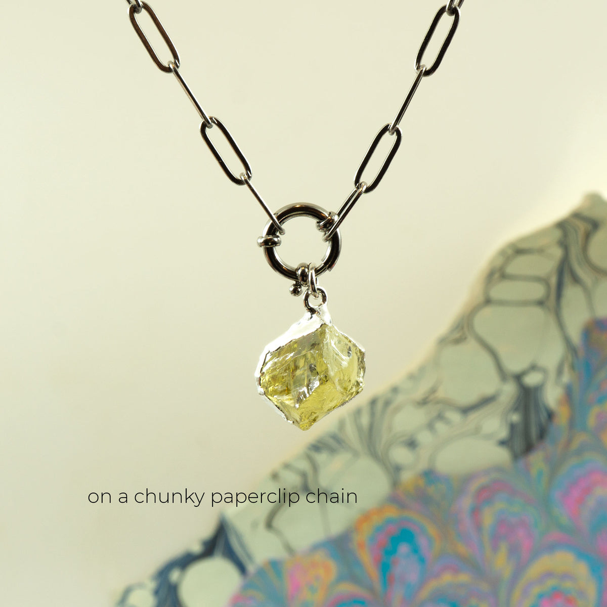 A necklace with a faceted pale yellow Lemon Quartz gemstone pendant on a chunky black paperclip chain