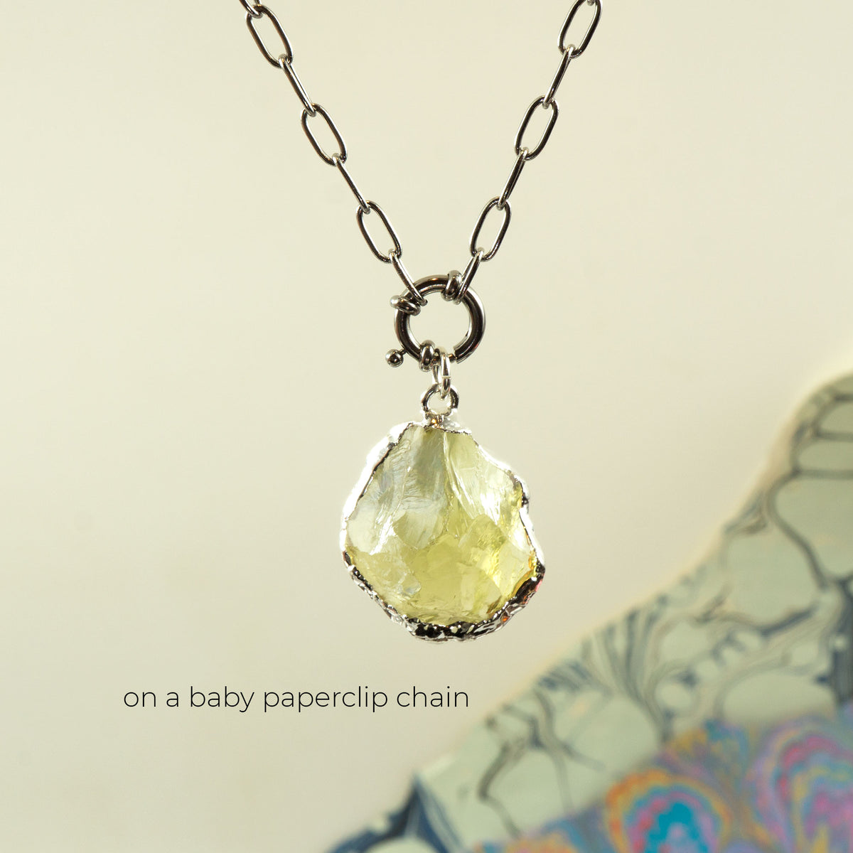 A silver paperclip chain necklace with a raw, faceted pale Lemon Quartz gemstone pendant