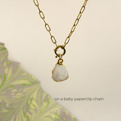 A gold paperclip chain necklace with a raw, irregular-shaped white Rainbow Moonstone stone pendant