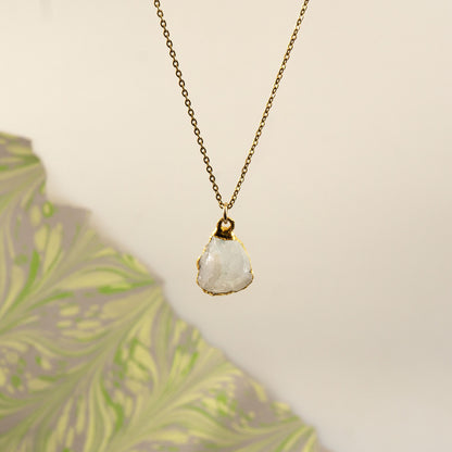A delicate gold chain necklace with a raw, irregular-cut white Rainbow Moonstone stone pendant