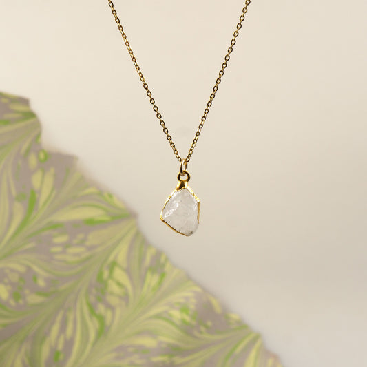 A delicate gold chain necklace with a raw, irregular-cut white Rainbow Moonstone stone pendant.