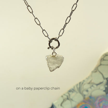 A silver paperclip chain necklace with a small ring clasp holding a rough, irregular clear Rainbow Moonstone pendant