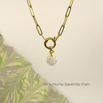 A gold paperclip chain necklace with a small ring connector and a teardrop-shaped white Rainbow Moonstone pendant,