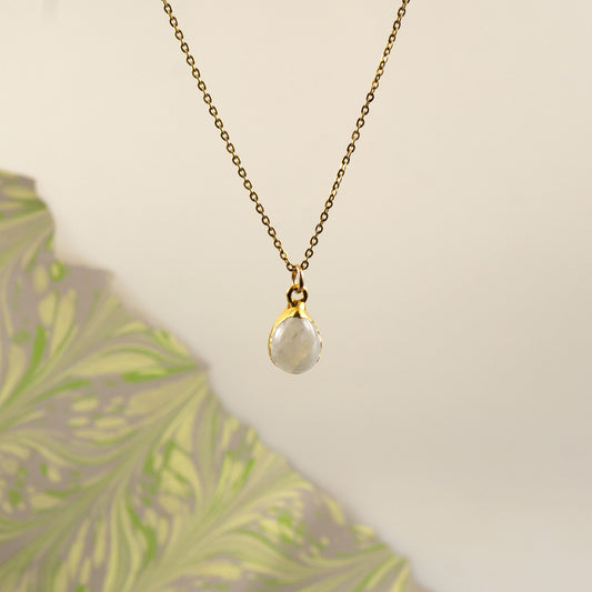 A delicate gold chain necklace with a teardrop-shaped white Rainbow Moonstone pendant