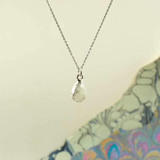 A silver chain necklace with a teardrop-shaped clear faceted Rainbow Moonstone pendant