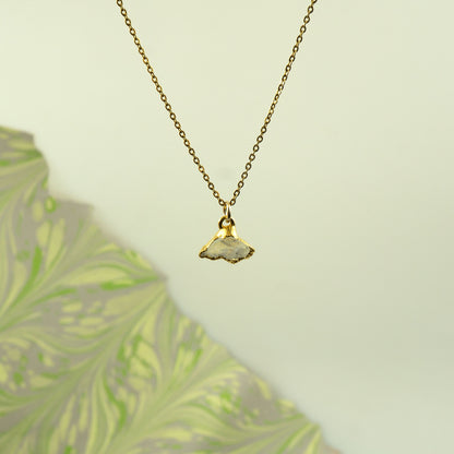 A gold chain necklace with a small pendant made from a natural, polished white Rainbow Moonstone.