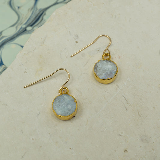 Round raw white moonstone earrings on hooks finished in gold.