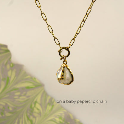 A gold paperclip chain necklace with a irregular white pearl pendant
