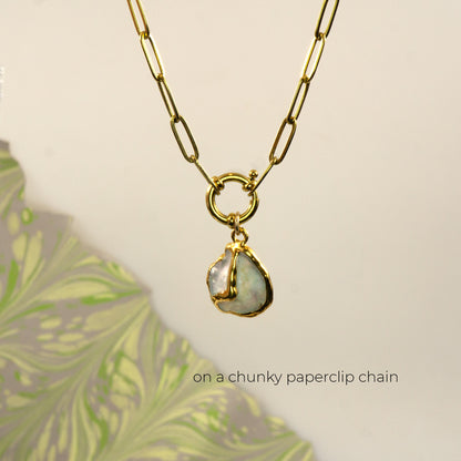 A gold paperclip chain necklace with a gold ring clasp a irregular iridescent pearl pendant