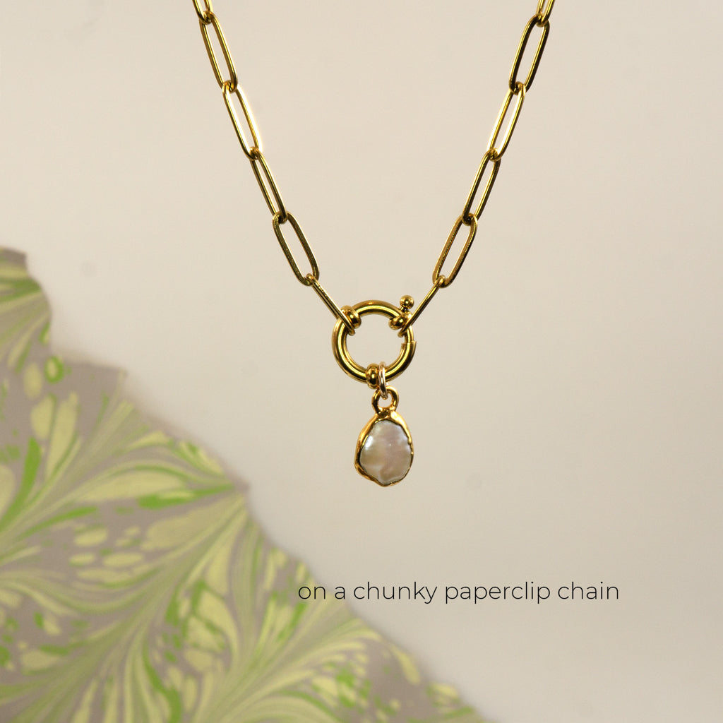 A gold paperclip chain necklace with a toggle clasp and a small irregular pearl pendant