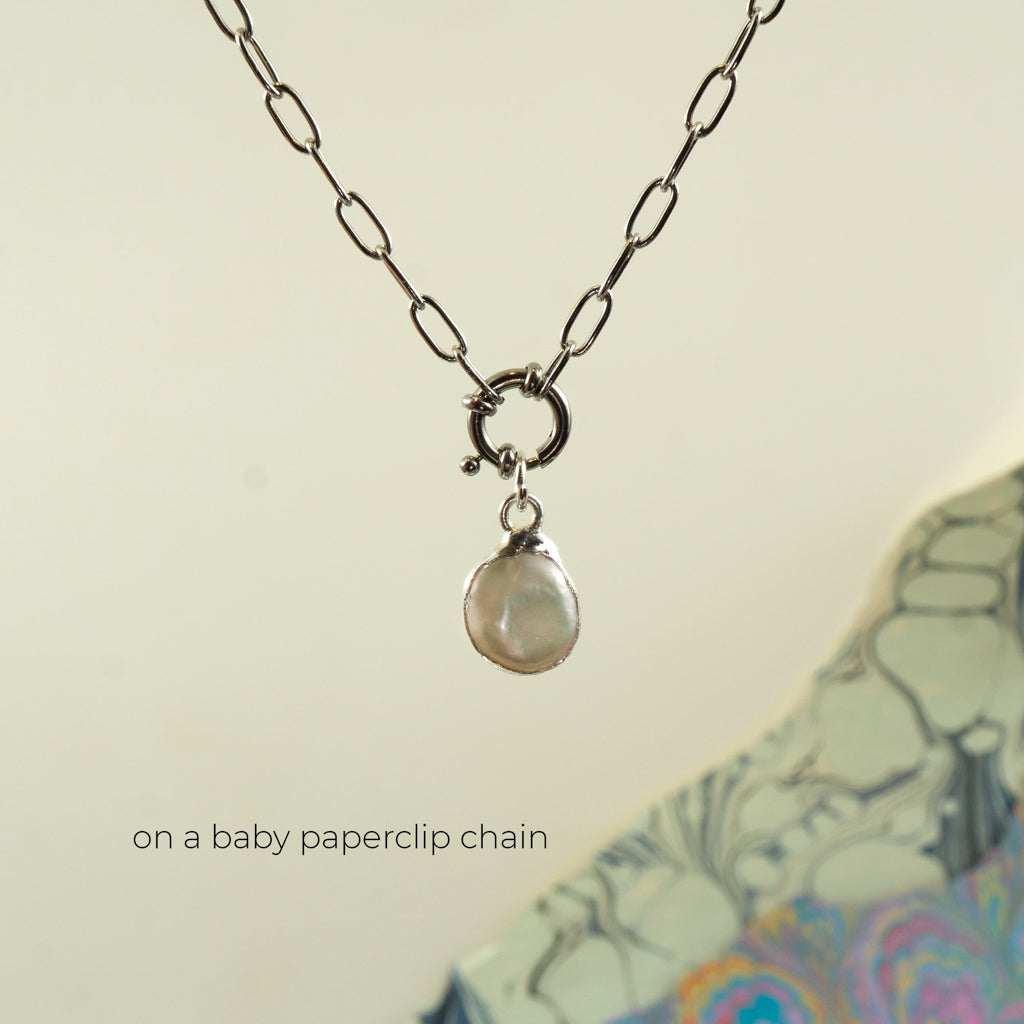 A silver paperclip chain necklace with a small ring clasp and a baroque pearl pendant,