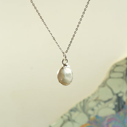 A silver chain necklace with a  irregular-shaped pearl pendant, 