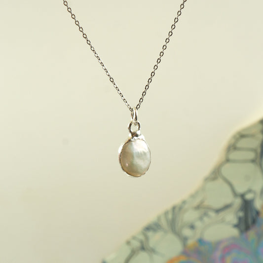 A silver chain necklace with a  irregular-shaped pearl pendant, 