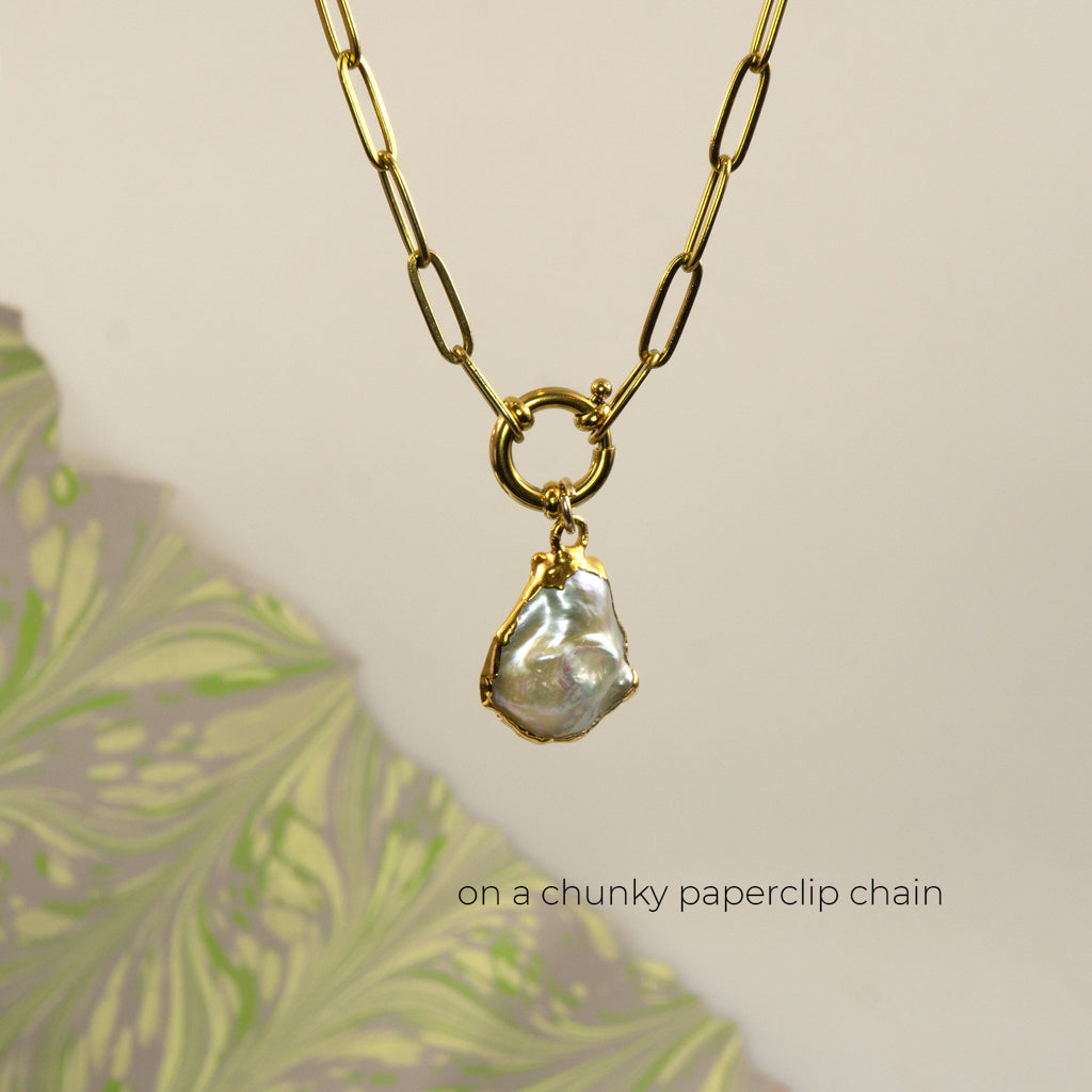 A gold paperclip chain necklace with a large ring clasp and an irregular Keshi pearl pendant,