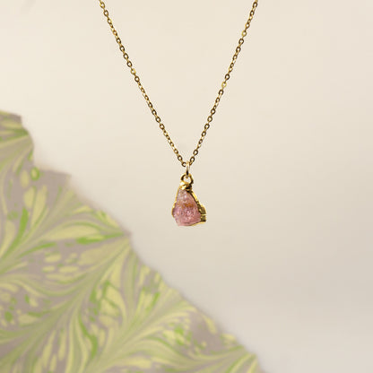 A delicate gold chain necklace with a raw Pink Tourmaline gemstone pendant