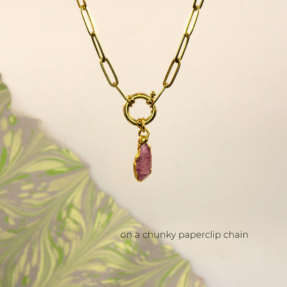 A gold paperclip chain necklace with a ring clasp and a small raw Pink Tourmaline gemstone pendant.