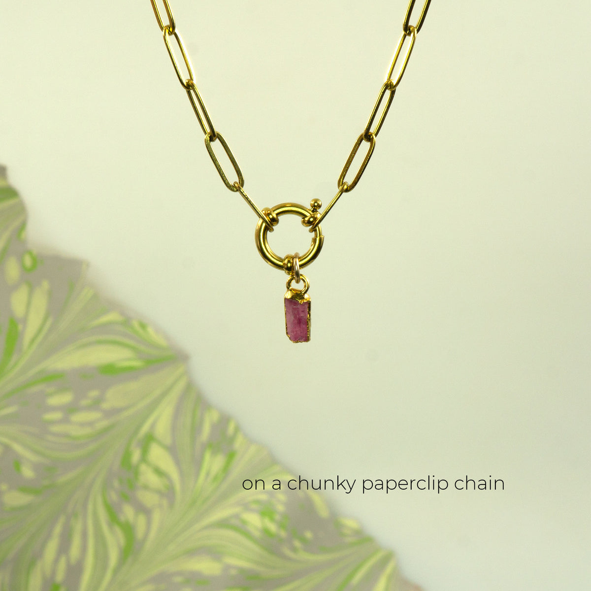 A gold paperclip chain necklace with a small rectangular Pink Tourmaline gemstone pendant