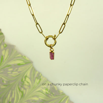 A gold paperclip chain necklace with a small rectangular Pink Tourmaline gemstone pendant