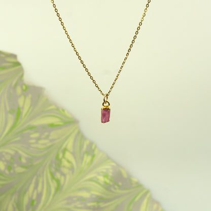 A delicate gold chain necklace with a small rectangular Pink Tourmaline gemstone pendant