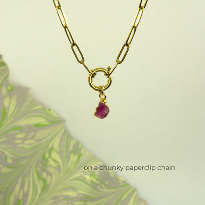 A gold paperclip chain necklace with a small ring clasp and a dangling raw Pink Tourmaline gemstone