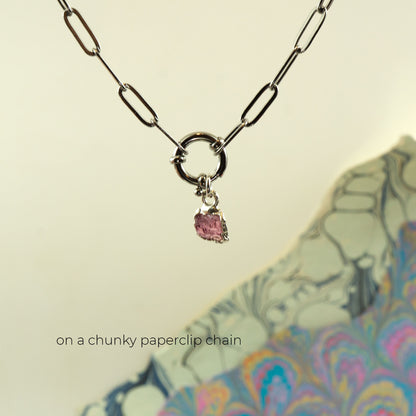 A silver paperclip chain necklace with a circular ring clasp and a small dangling Pink Tourmaline gemstone