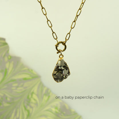 A gold paperclip chain necklace with a raw, teardrop-shaped Pyrite gemstone pendant