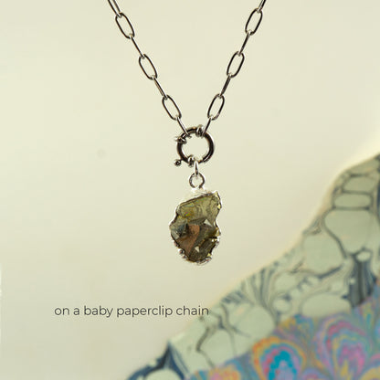 A necklace with a baby silver paperclip chain and a raw, rough,metallic pyrite gemstone pendant