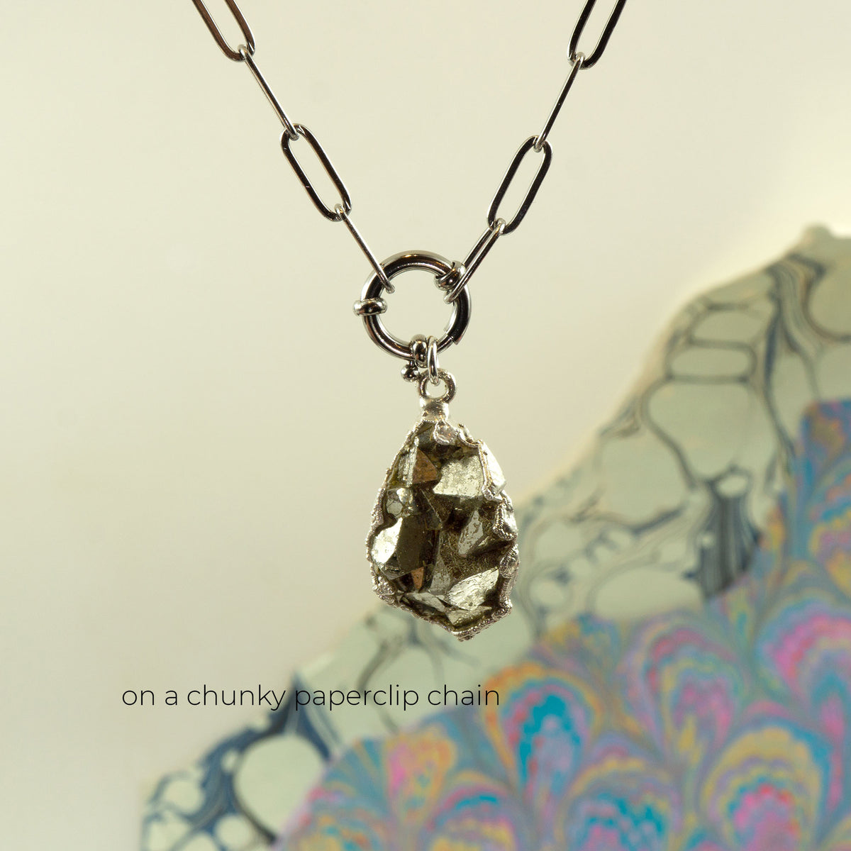 A chunky paperclip chain necklace with a raw, metallic gold pyrite pendant,