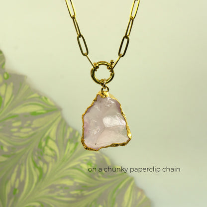 A gold chunky paperclip chain necklace with a raw, irregular pale pink rose quartz stone pendant