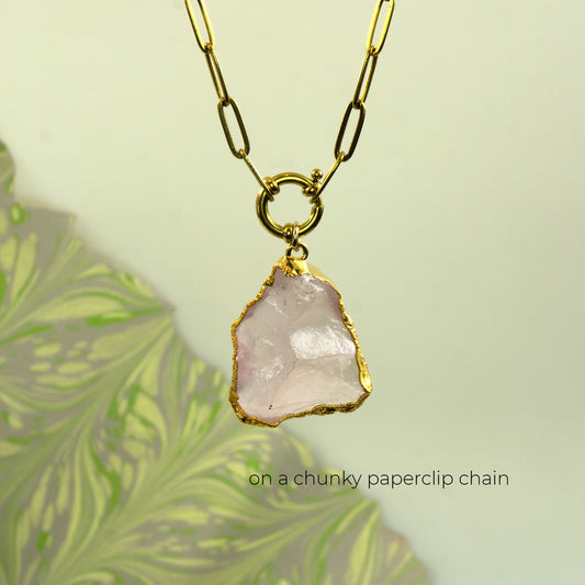 A gold chunky paperclip chain necklace with a raw, irregular pale pink rose quartz stone pendant
