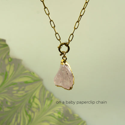 A gold baby paperclip chain necklace with a raw, irregular-cut pale pink raw quartz stone pendant.