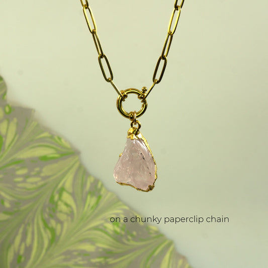 A gold chunky paperclip chain necklace with a raw, irregularly shaped pale pink rose quartz stone pendant
