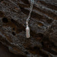 Silver bottle of beer pendant on a chain against a textured brown background